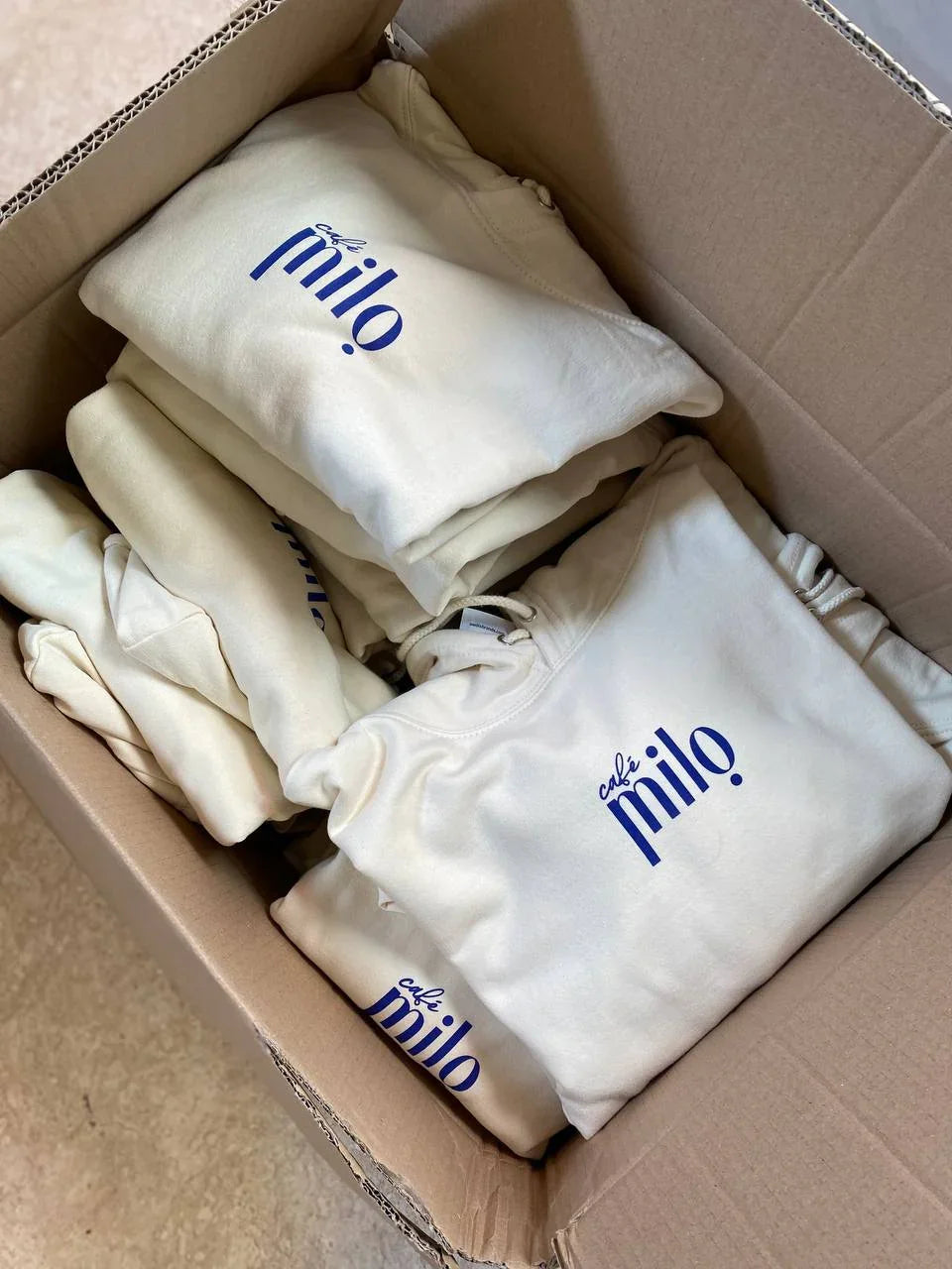 Sweats unisexe blancs 'café milo' pliés dans une boîte, streetwear fait main à Antibes